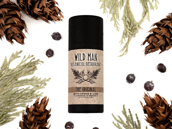 Wild Man Botanical Deodorant in a 2.4 oz biodegradable paper tube. Dried herbs surround.